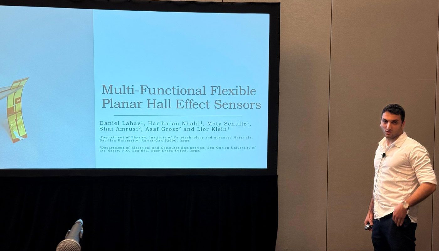Daniel Lahav on stage presenting the talk &ldquo;Multi-Functional Flexible Planar Hall Effect Sensors&rdquo;, title slide on screen